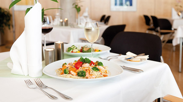 Gedeckter Tisch mit einem Pasta-Gericht und einem Glas Wein