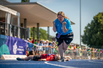 Bild zeigt zwei Läuferinnen nach Zieleinlauf. Eine liegt am Boden, streckt die Arme auseinander, die andere windet sich vor Freude